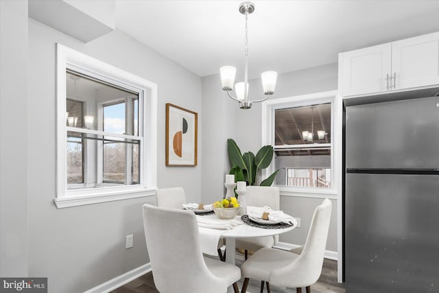 dining space featuring a notable chandelier, dark wood-style flooring, and baseboards