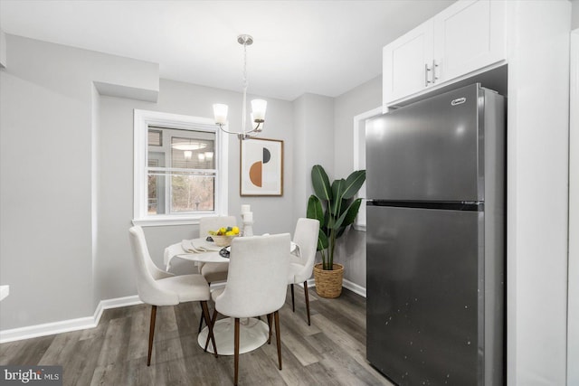 dining area featuring an inviting chandelier, baseboards, and wood finished floors