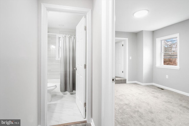 hall with marble finish floor, baseboards, visible vents, and light colored carpet