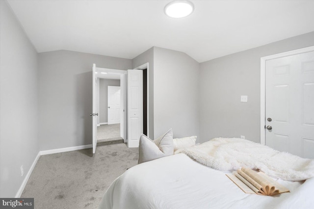 bedroom with vaulted ceiling, baseboards, and light colored carpet