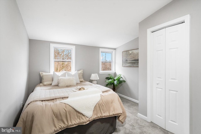 bedroom with light carpet, baseboards, vaulted ceiling, and a closet