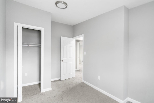 unfurnished bedroom featuring light carpet, baseboards, and a closet