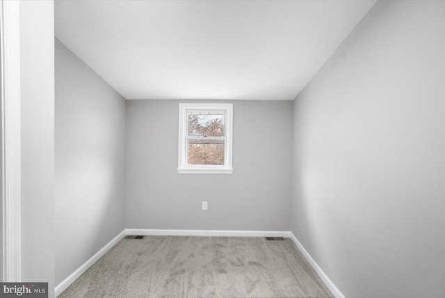 empty room with baseboards, visible vents, and light colored carpet