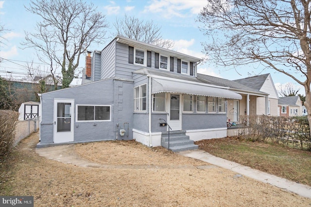 view of front of home with entry steps, a storage shed, a chimney, and fence