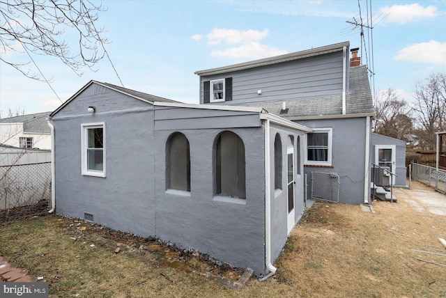 rear view of house featuring a yard, stucco siding, a shingled roof, crawl space, and fence