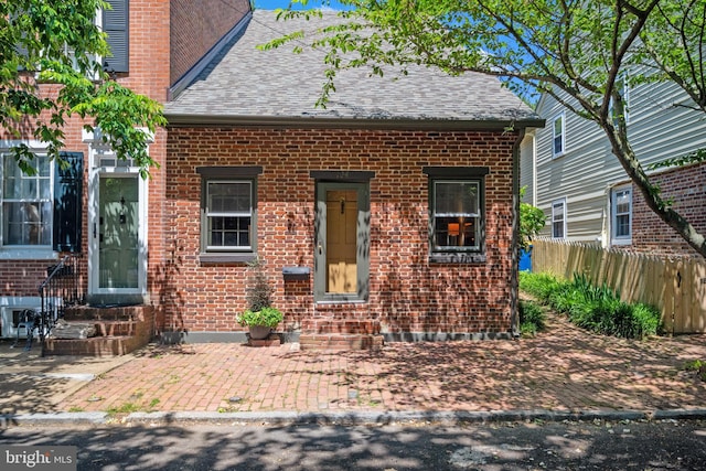 view of front facade with brick siding and roof with shingles