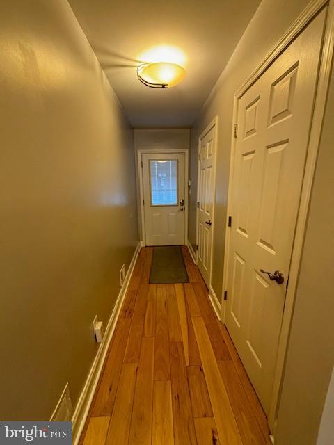 hall with light wood-type flooring and baseboards