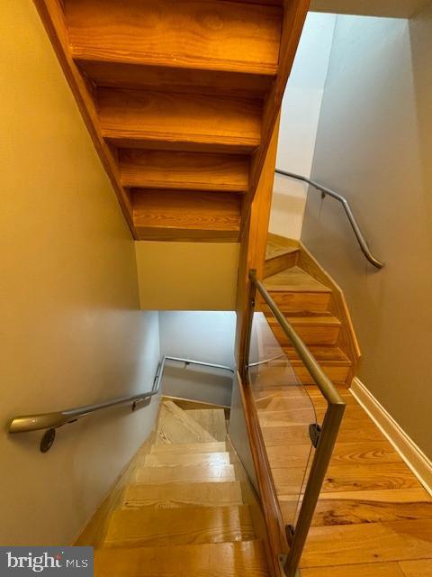 staircase featuring baseboards and wood finished floors