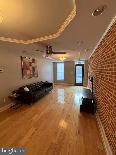 unfurnished living room with brick wall, light wood-type flooring, and crown molding