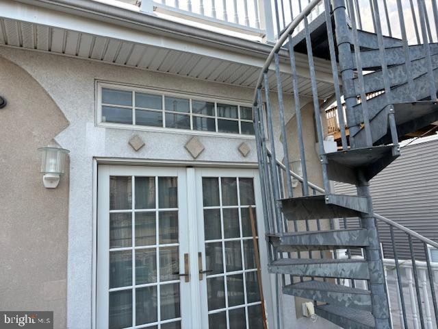 view of exterior entry featuring french doors and stucco siding