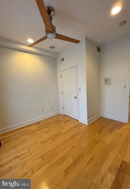 empty room with baseboards, light wood-type flooring, visible vents, and a ceiling fan