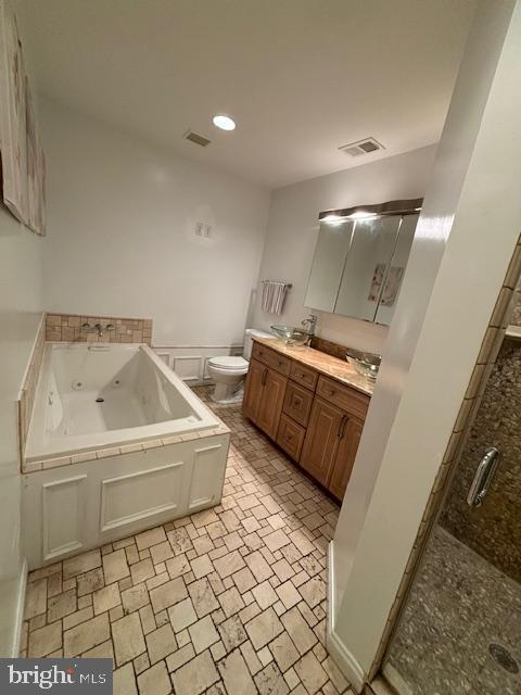 bathroom featuring double vanity, visible vents, toilet, and a whirlpool tub