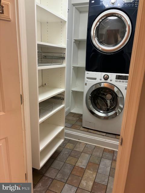 clothes washing area featuring stacked washer and dryer and laundry area