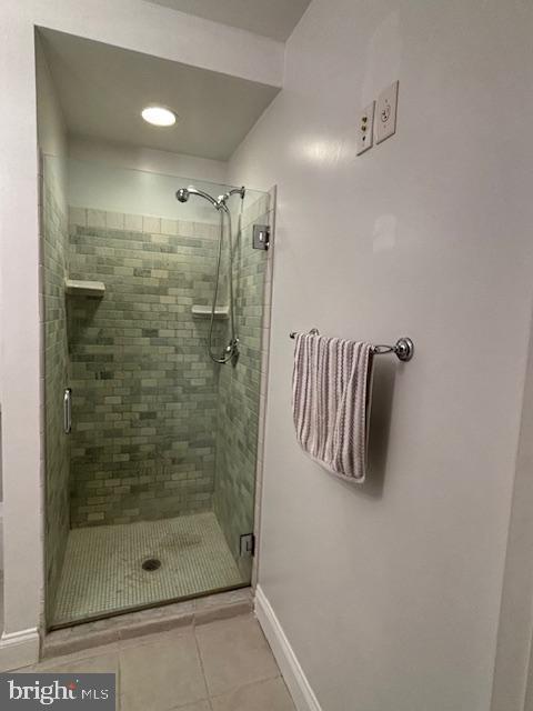 full bathroom with tile patterned flooring, a shower stall, and baseboards