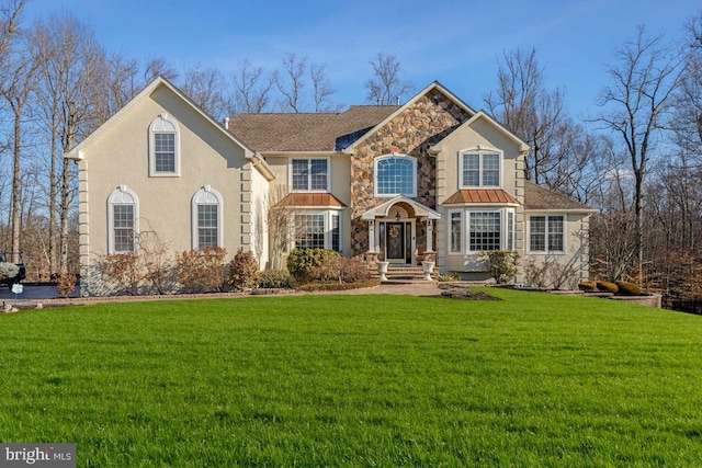 view of front of home with stucco siding, a standing seam roof, metal roof, stone siding, and a front lawn