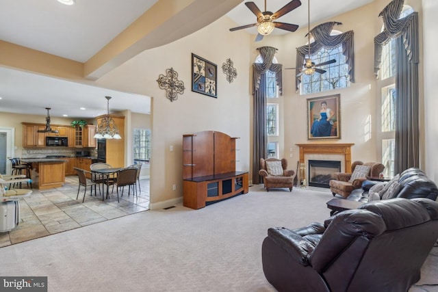 living area with baseboards, a tiled fireplace, light colored carpet, a towering ceiling, and recessed lighting