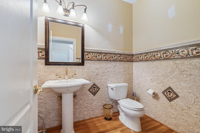 bathroom with toilet, a wainscoted wall, tile walls, and wood finished floors