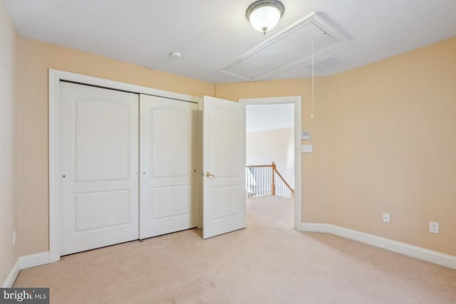 unfurnished bedroom featuring attic access, baseboards, a closet, and light colored carpet