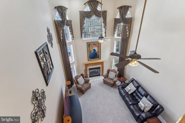 living area with carpet flooring, a fireplace, plenty of natural light, and a high ceiling