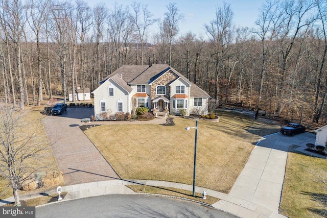 view of front of property with driveway, a forest view, stucco siding, and a front yard