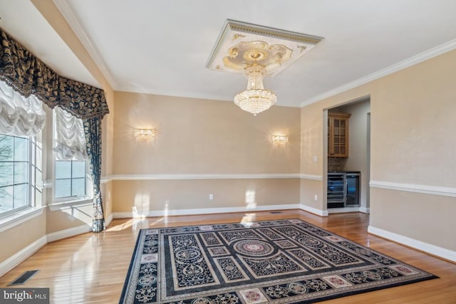 interior space featuring a chandelier, wood finished floors, visible vents, and crown molding