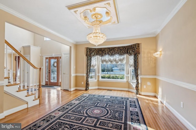 entrance foyer featuring crown molding, stairway, plenty of natural light, and an inviting chandelier