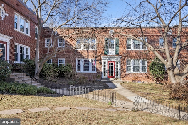 multi unit property with brick siding, a fenced front yard, and a gate