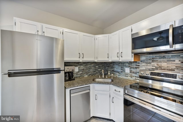 kitchen with tasteful backsplash, appliances with stainless steel finishes, dark stone counters, and a sink