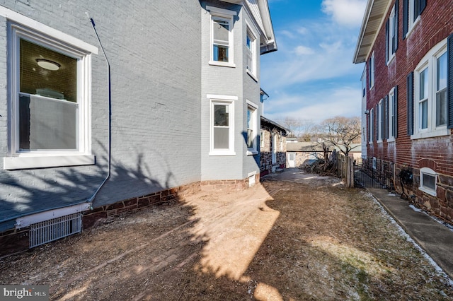 view of property exterior with brick siding and fence