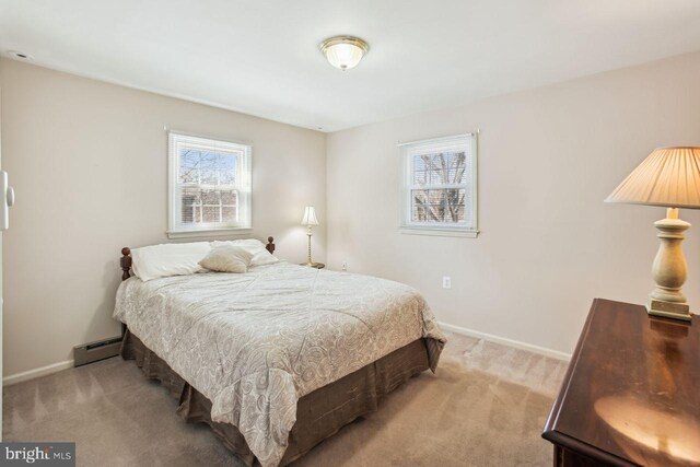 bedroom with light carpet, baseboard heating, and baseboards