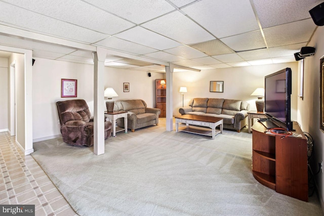 carpeted living area featuring a paneled ceiling and baseboards