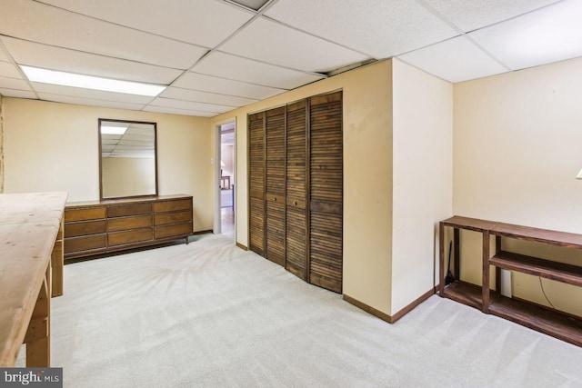 unfurnished bedroom with a drop ceiling, baseboards, a closet, and carpet floors