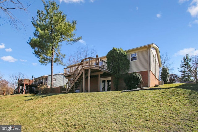 rear view of property featuring brick siding, stairway, a lawn, and a deck