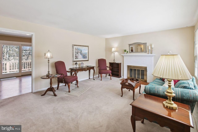 living room featuring baseboards, a brick fireplace, and carpet flooring