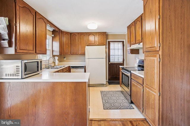 kitchen with under cabinet range hood, stainless steel appliances, light countertops, and a sink