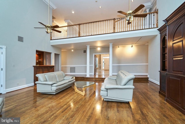 living area with visible vents, baseboards, wood finished floors, and a ceiling fan