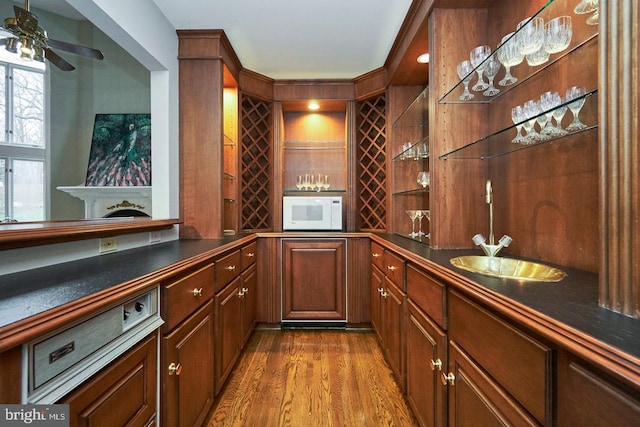 bar with a ceiling fan, a sink, wood finished floors, indoor wet bar, and white microwave