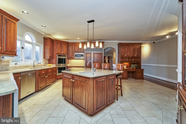 kitchen featuring a sink, stainless steel appliances, arched walkways, and light stone counters