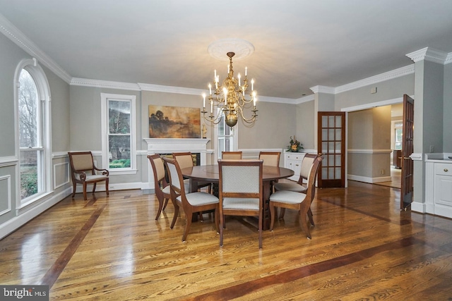 dining room featuring baseboards, a notable chandelier, wood finished floors, and ornamental molding