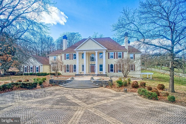 greek revival house featuring stucco siding and a chimney