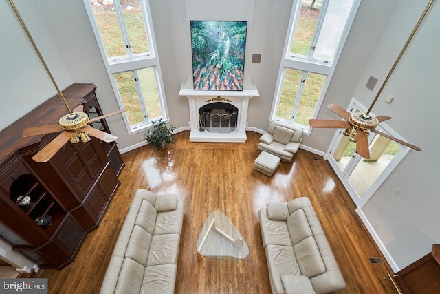 living room featuring a ceiling fan, wood finished floors, and a towering ceiling