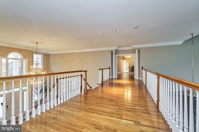 hall featuring an upstairs landing, a notable chandelier, crown molding, and wood finished floors