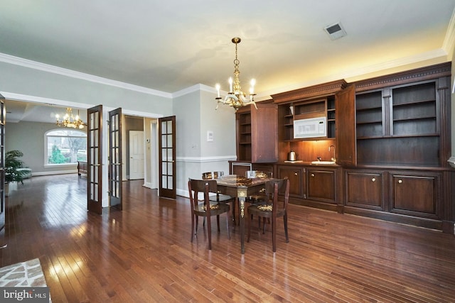 dining space featuring dark wood-style floors, french doors, an inviting chandelier, and ornamental molding