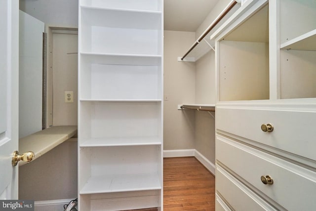 walk in closet with wood finished floors