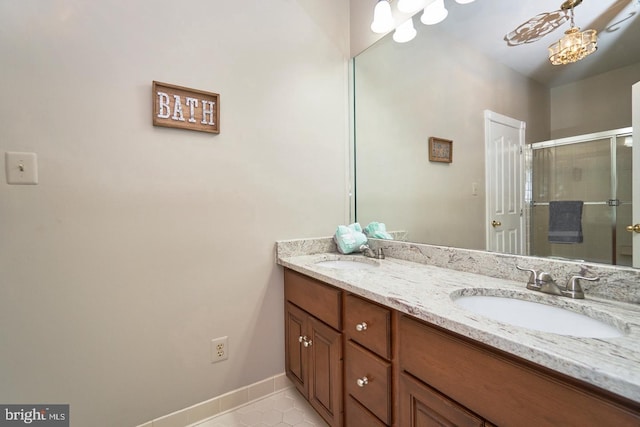 full bath with double vanity, baseboards, a stall shower, and a sink