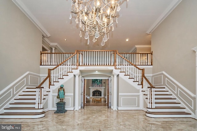 stairs with a high ceiling, a fireplace, crown molding, a decorative wall, and marble finish floor