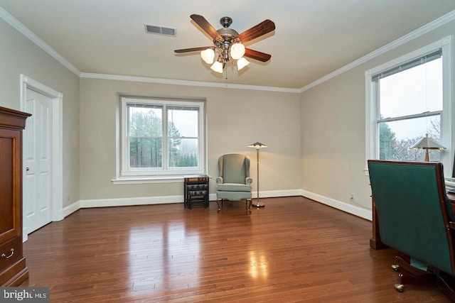 living area with visible vents, crown molding, baseboards, wood finished floors, and a ceiling fan