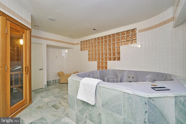 interior space featuring visible vents, tile walls, and a tub with jets