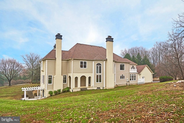 rear view of house featuring a lawn and a chimney