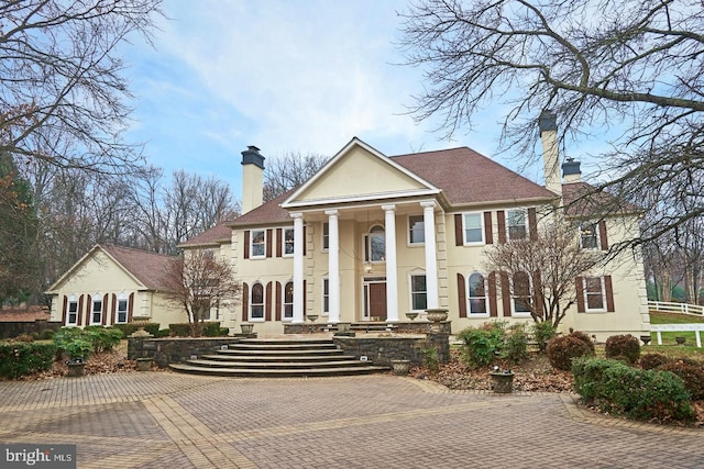 neoclassical / greek revival house with stucco siding and a chimney